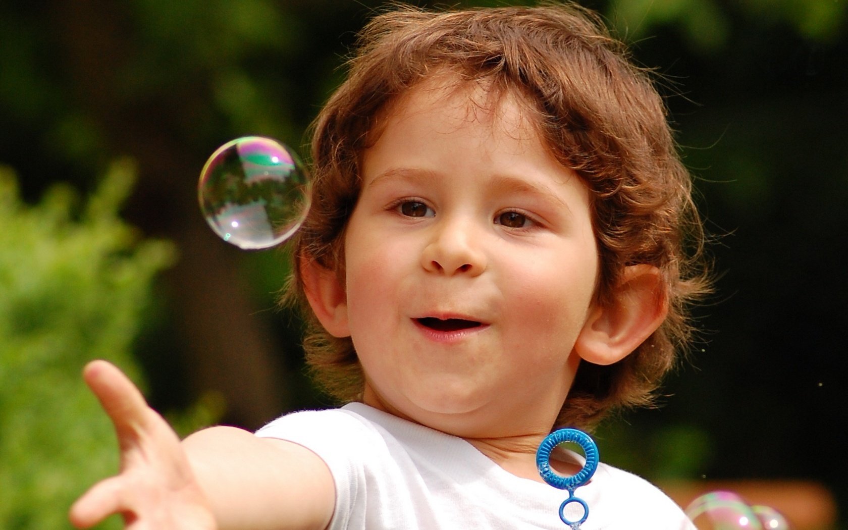 Удивленный мальчишка играет с мыльными пузырями