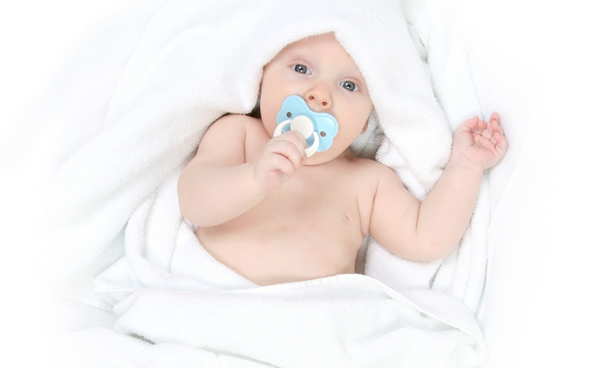 Малыш с соской во рту в белом одеяле