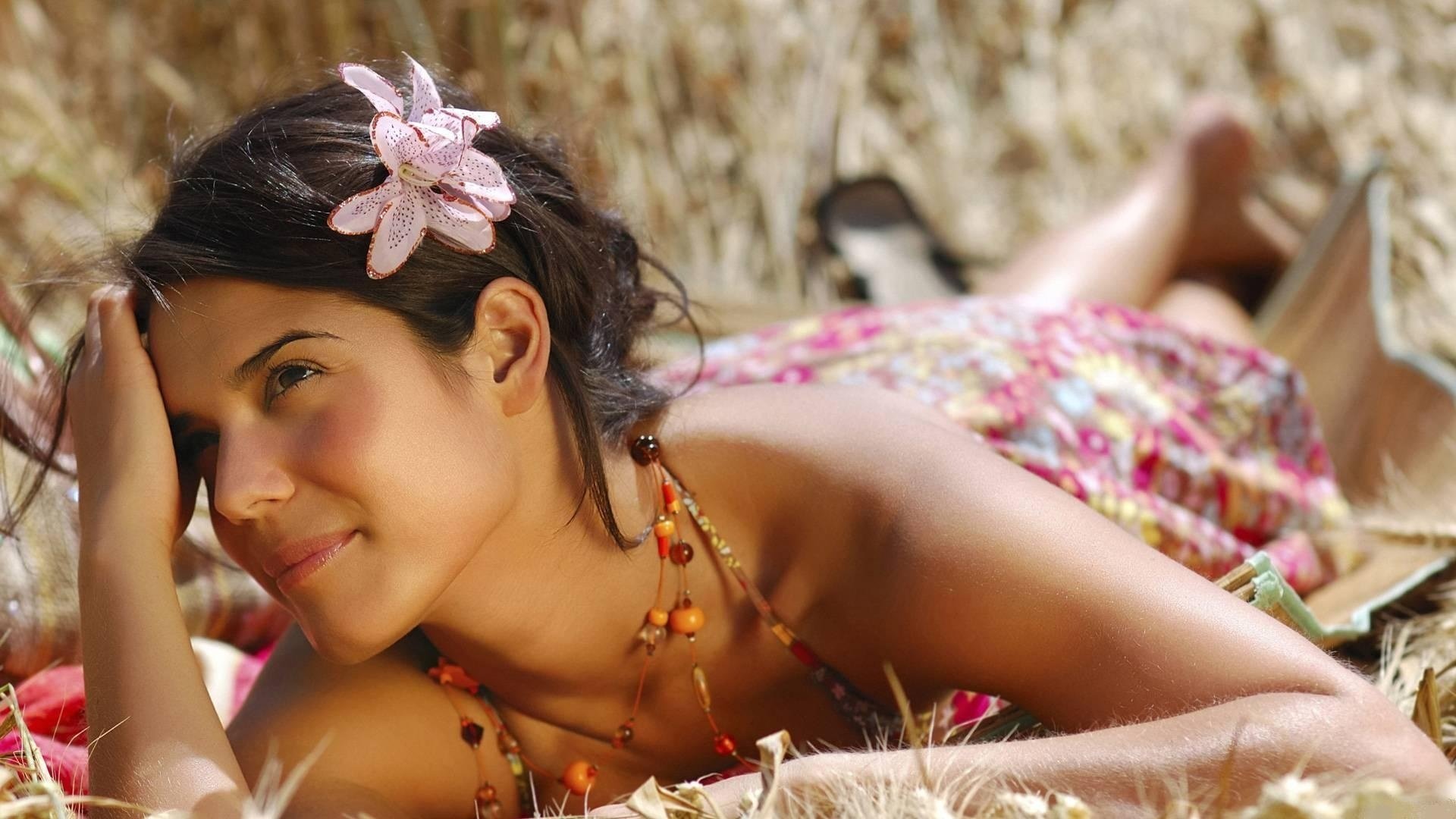 Красивая девушка с цветком в волосах лежит и заманчиво смотрит. Гавайские мотивы