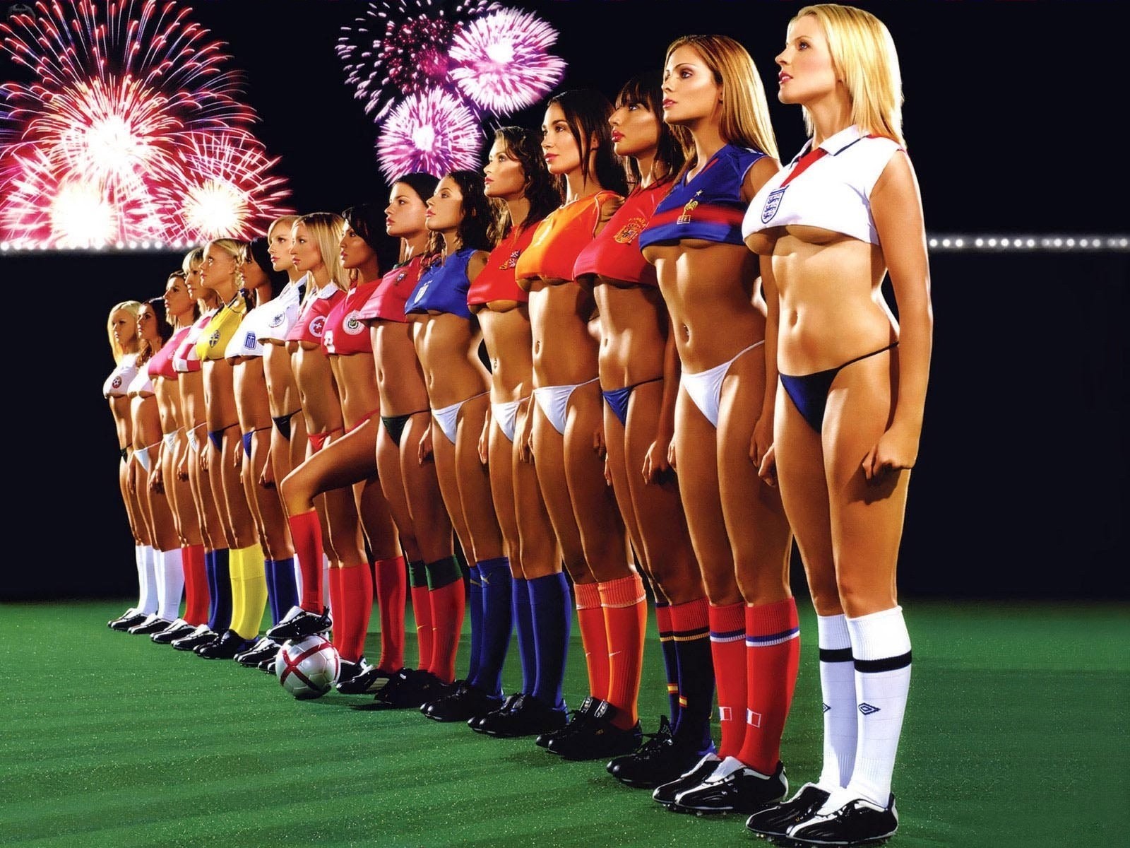 Сексуальная женская команда по футболу стоит на футбольном фоне и любуется салютом