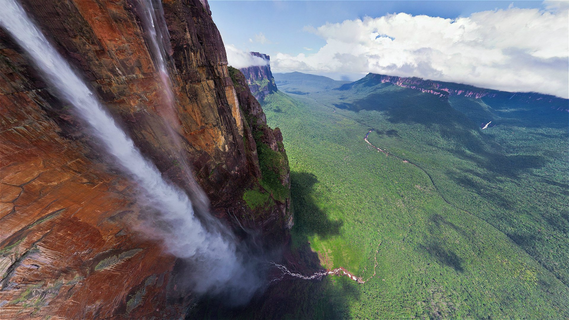 Высокой водопад с горами, зеленью и облаками