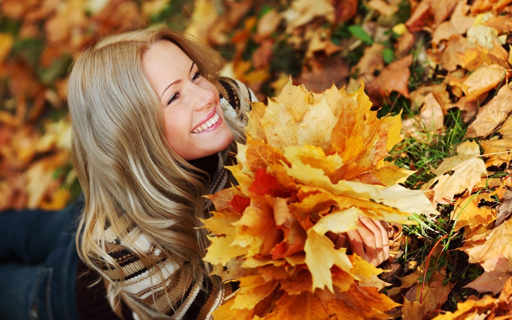 Улыбающаяся девушка с букетом из опавших листьев
