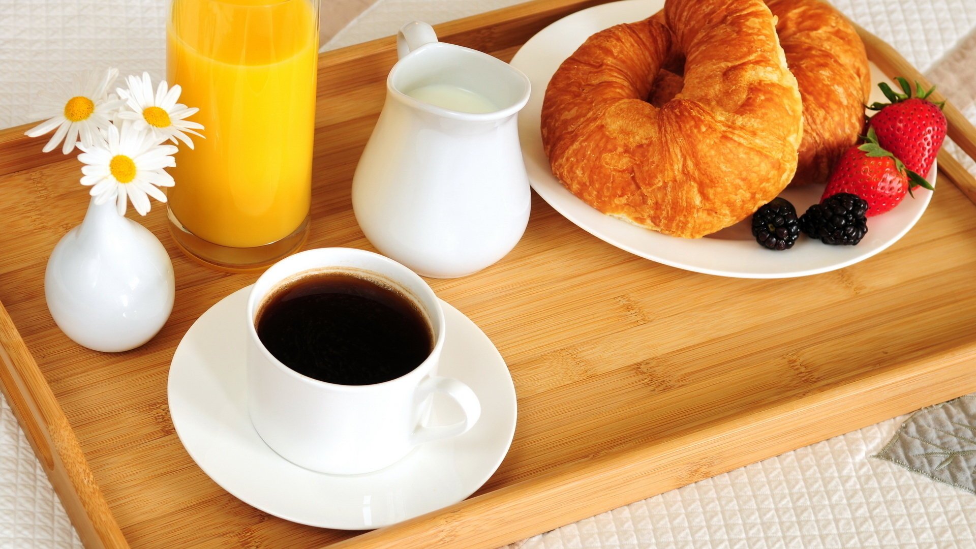 Чашка кофе с круасанами, ягодами, с молоком и апельсиновым соком, поданными на завтрак в постель