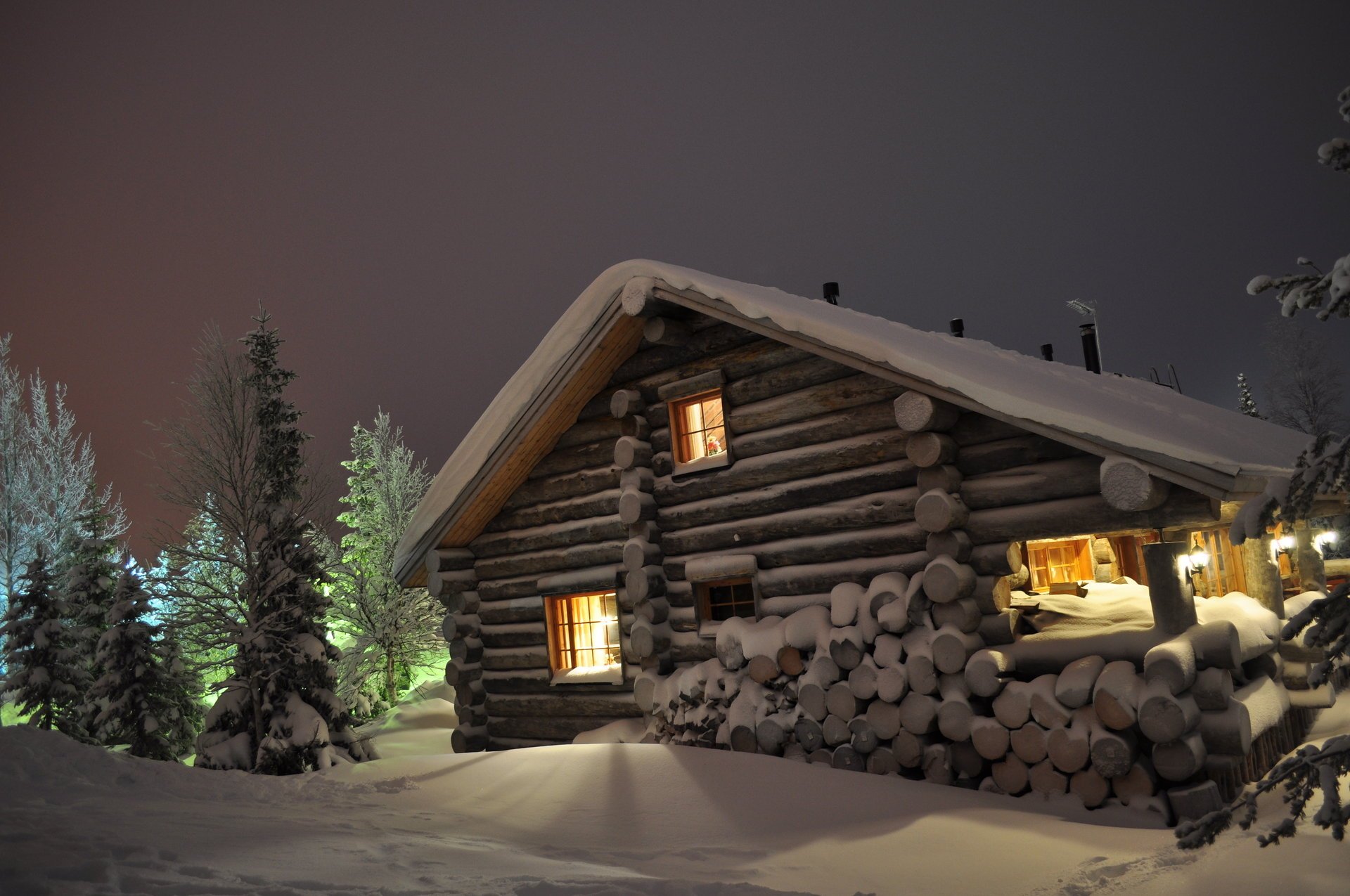 Дом зимней ночью со светом в окнах