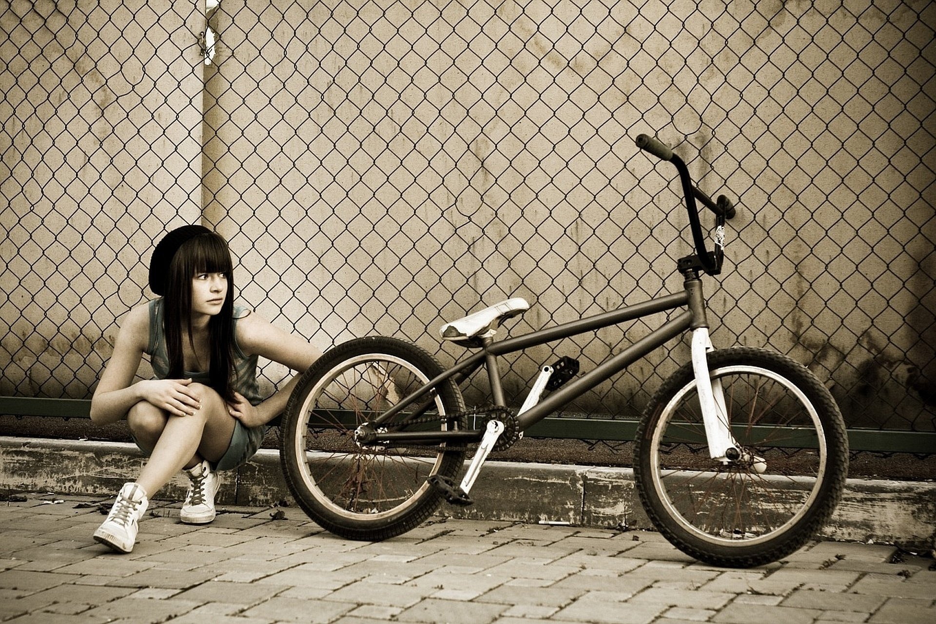 Девушка с велосипедом bmx вдоль забора в сетку