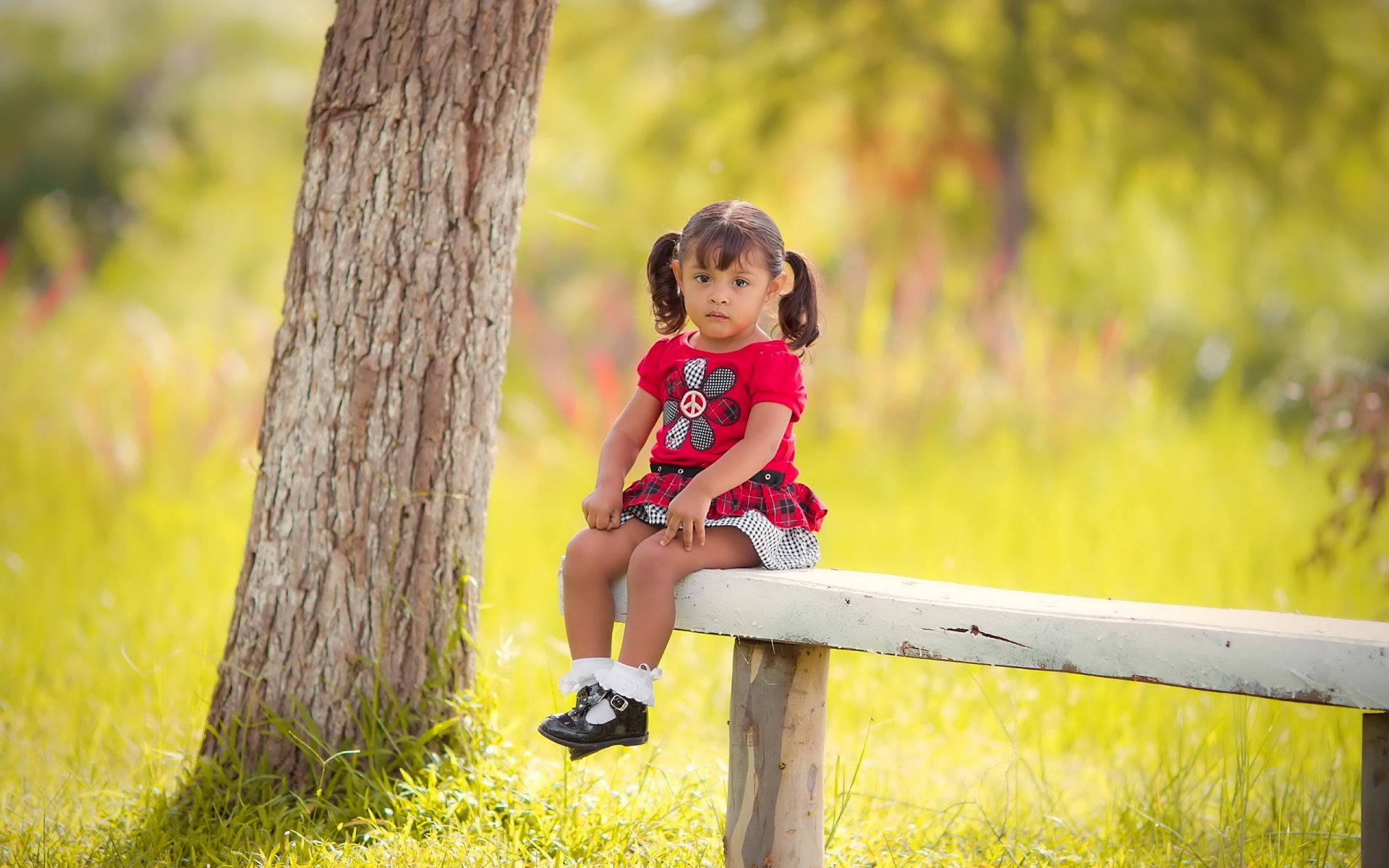 Маленькая девочка на скамейке в солнечном лесу Обои на рабочий стол.