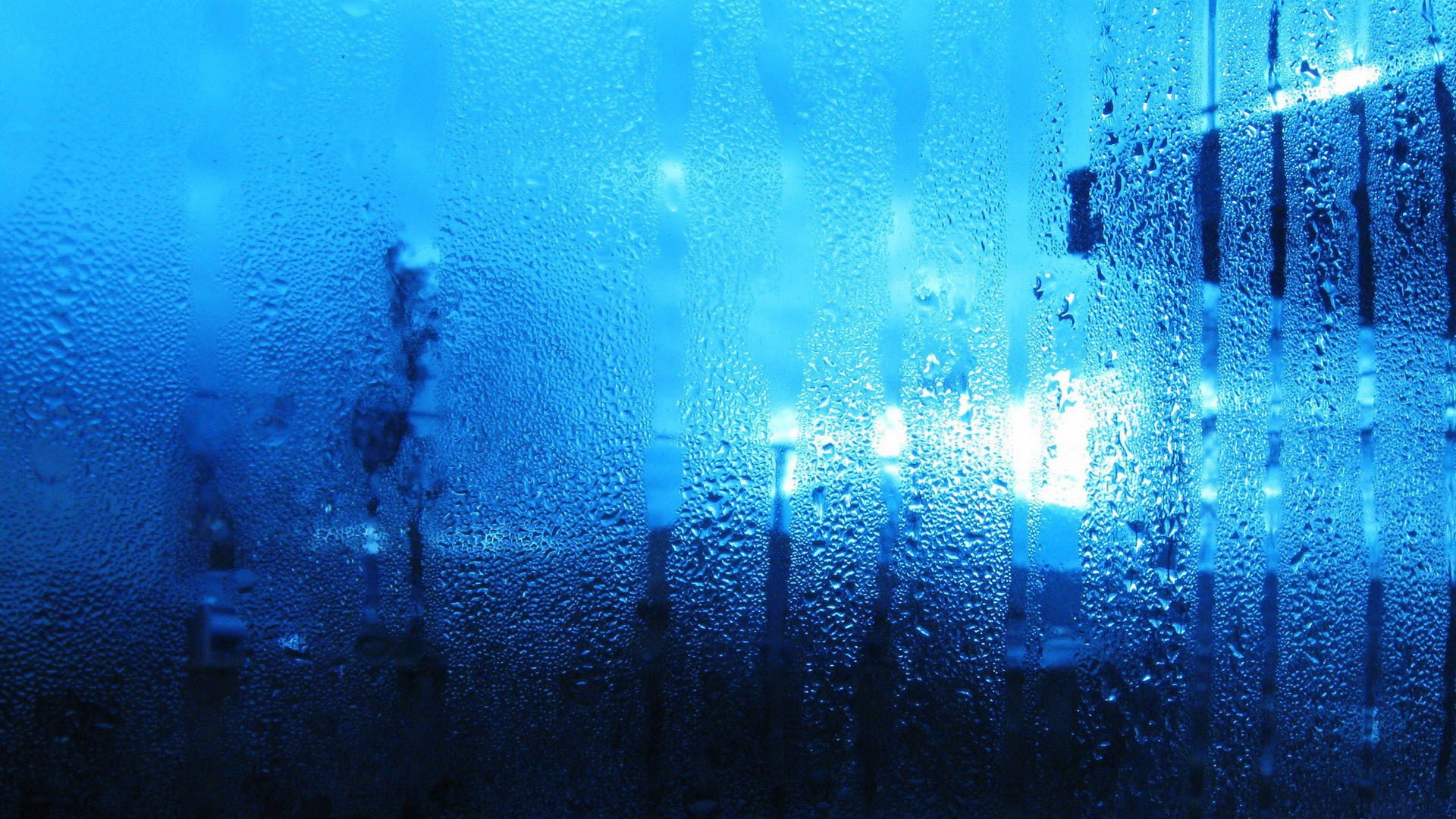 В стене капает вода. Капли на стекле. Стекло текстура. Стена воды. Синий дождь.