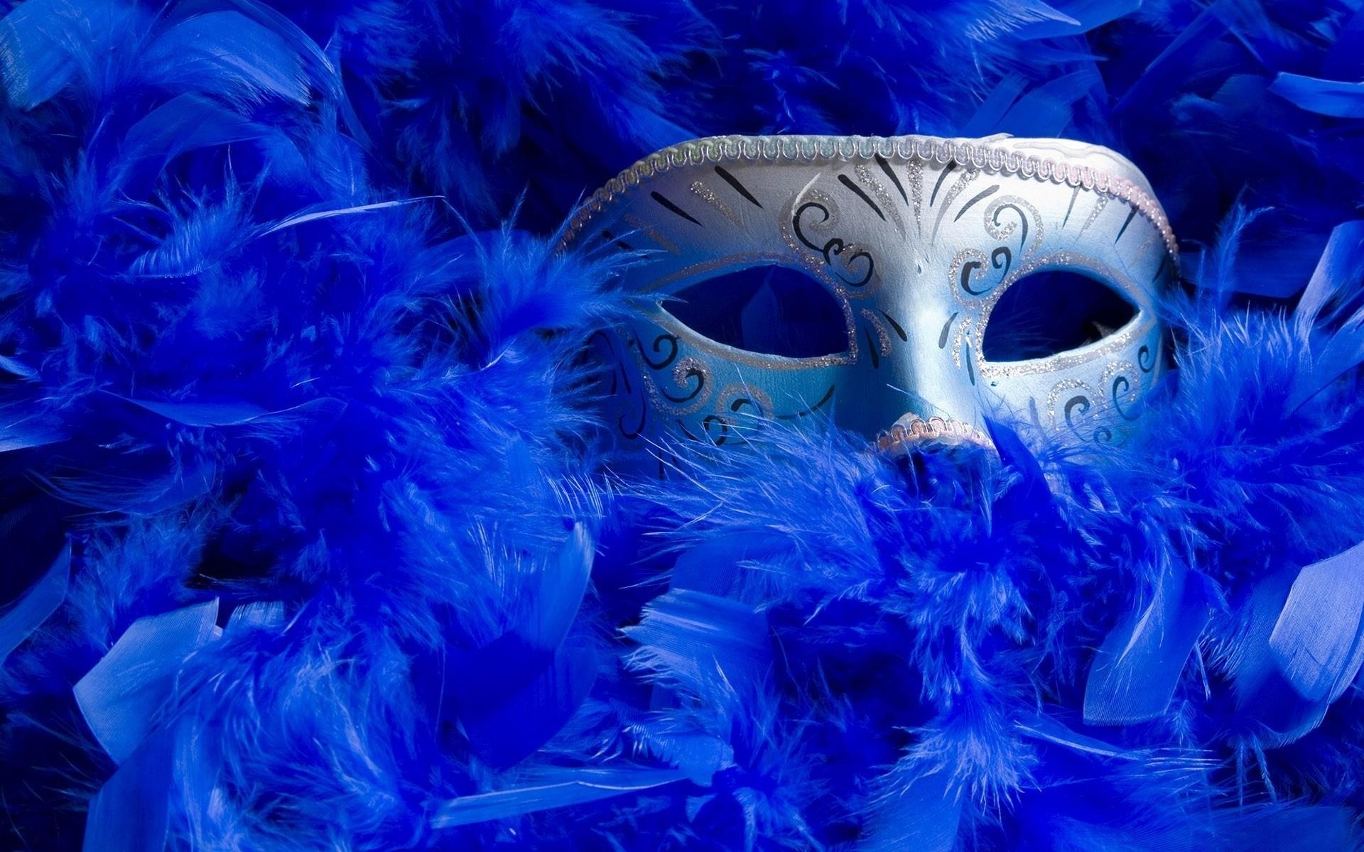 Карнавальная маска выглядывает из синих перьев