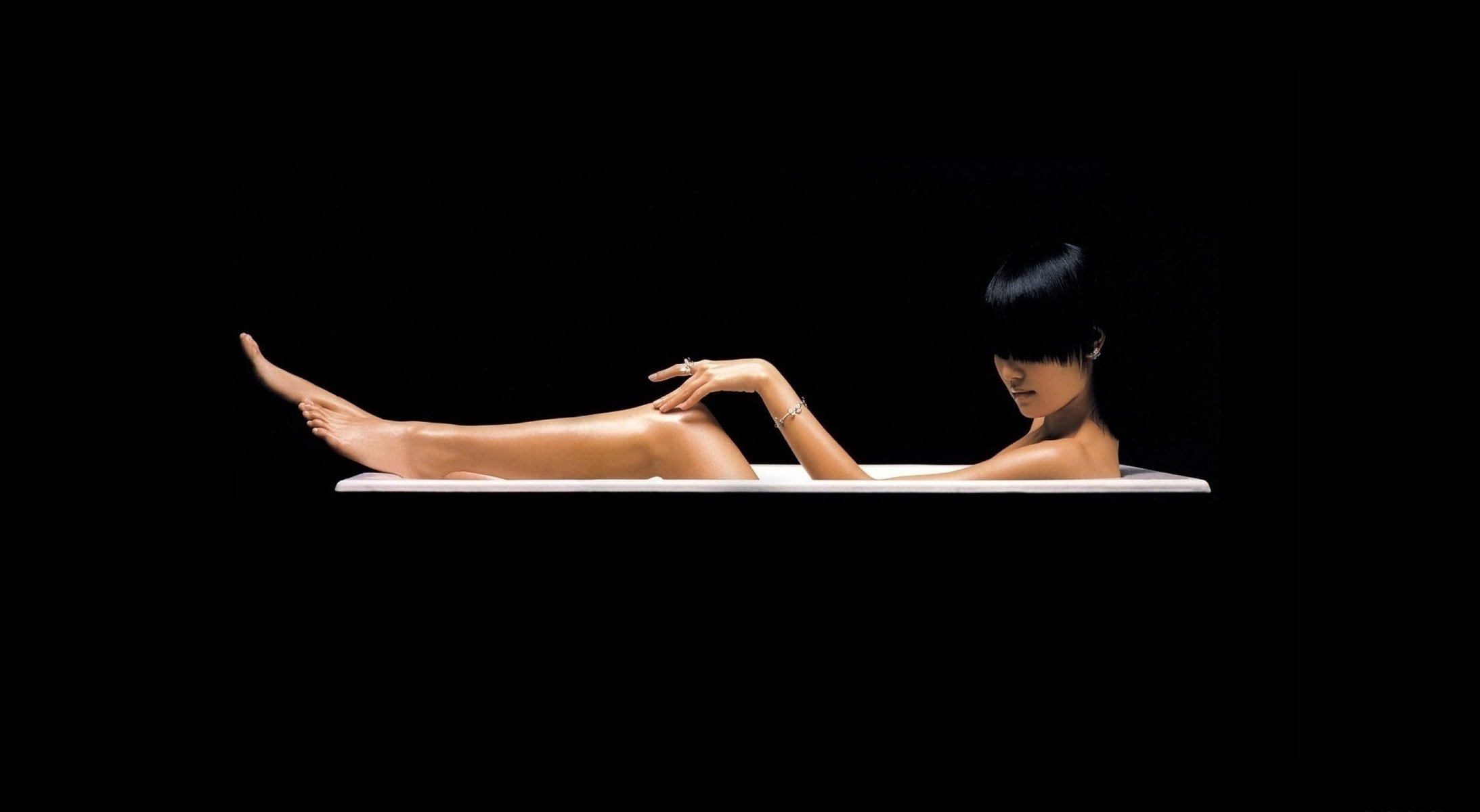 Девушка лежит в ванной на чёрном фоне