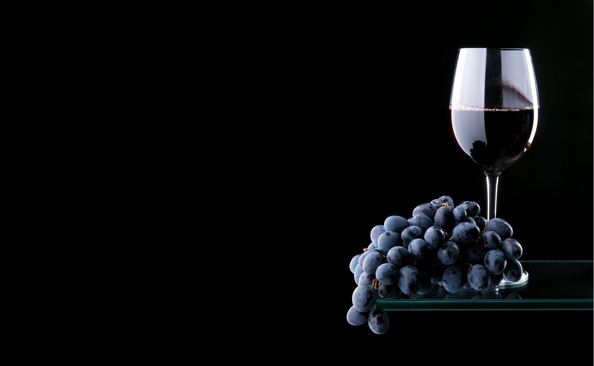 Красное вино с гроздью винограда на чёрном фоне