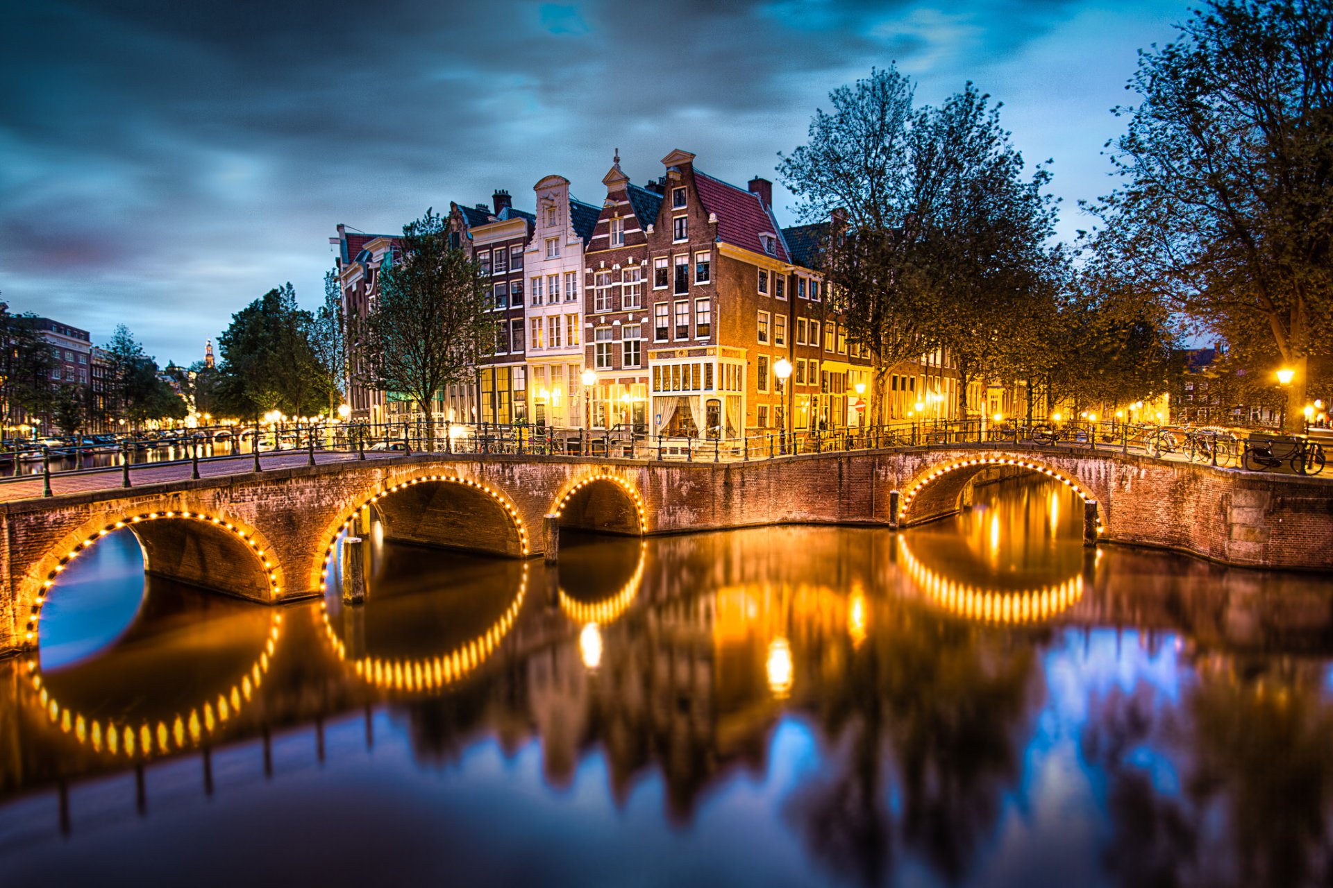 амстердам нидерланды город вечер небо тучи канал мост огни освещение река вода отражение дома улицы фонари деревья
