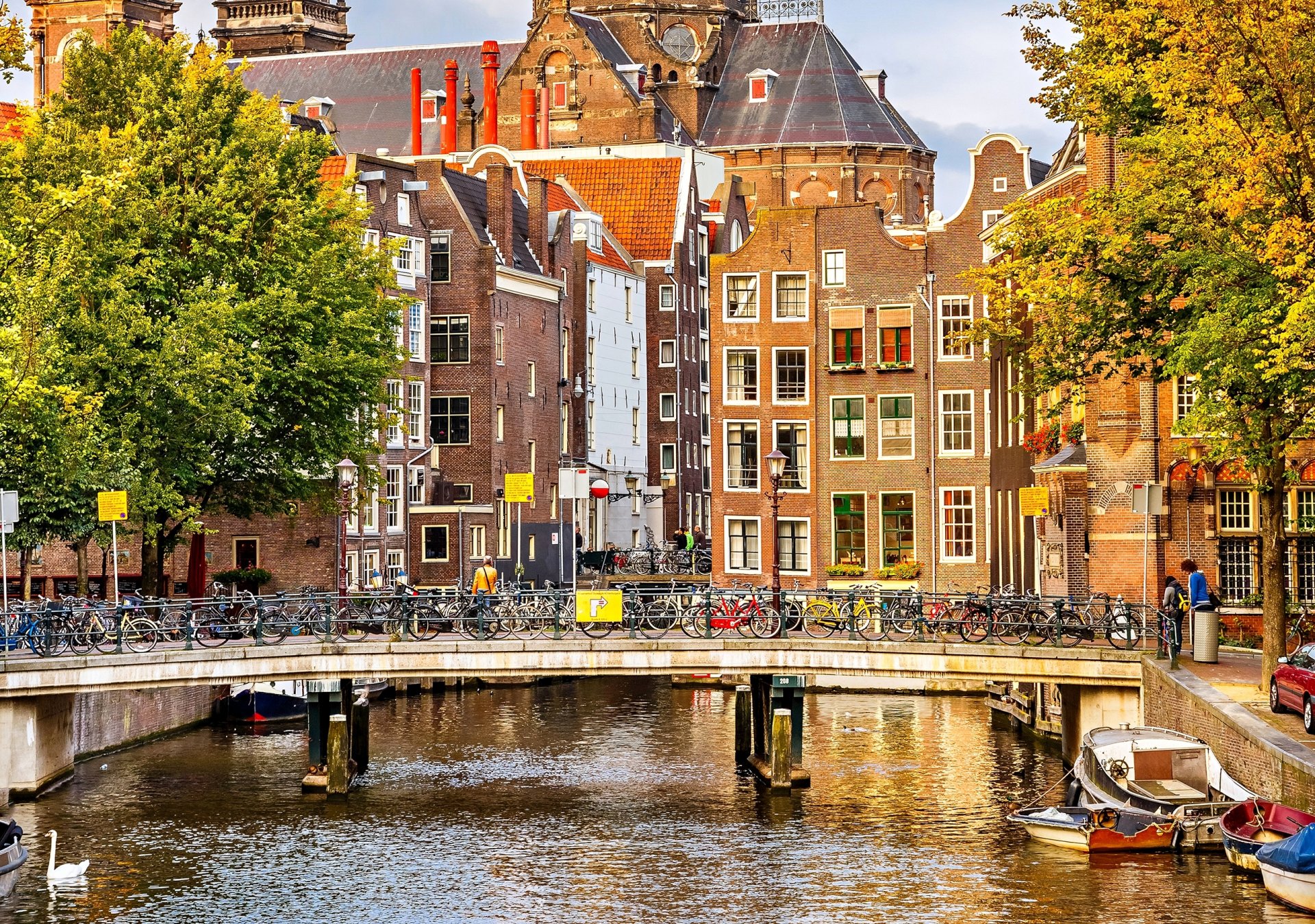 амстердам нидерланды осень деревья город дома здания архитектура мост велосипеды канал река лодки люди