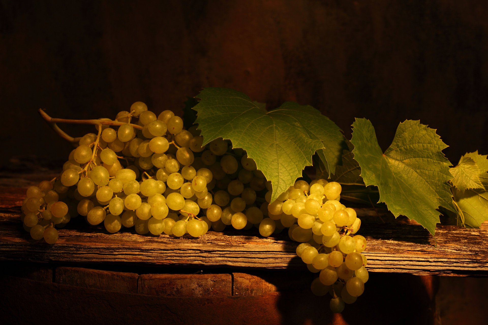 Грозди белого винограда с листьями на деревянном столе