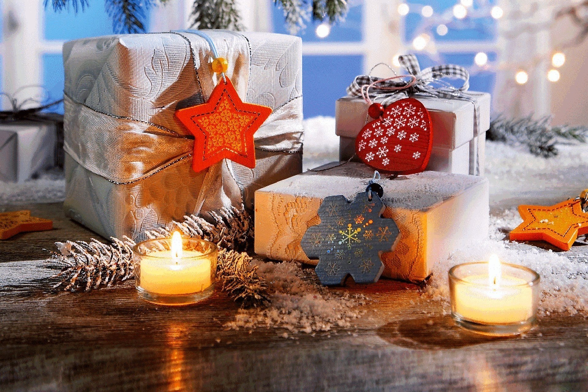 Подарки к рождеству в окружении свечей и еловых шишек