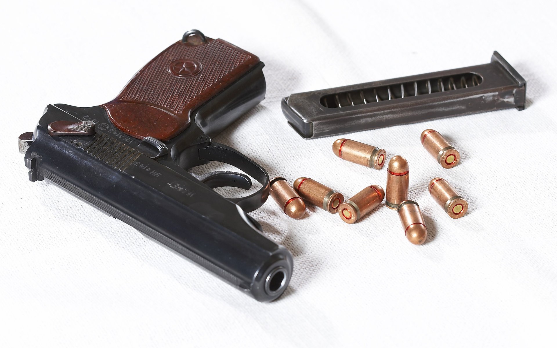 Пистолет Макарова с патронами на белом фоне