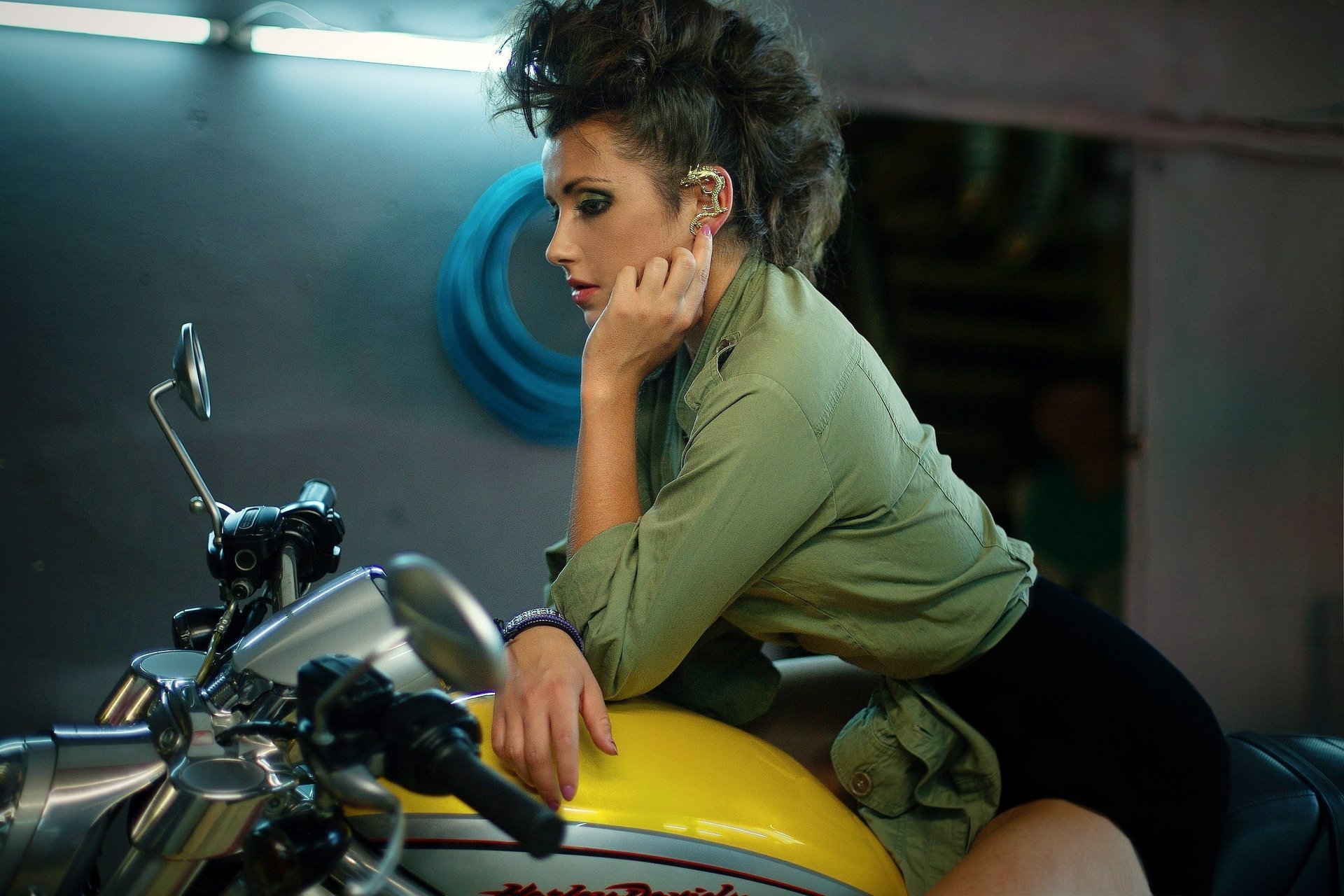 Девушка сидит в гараже на жёлтом мотоцикле