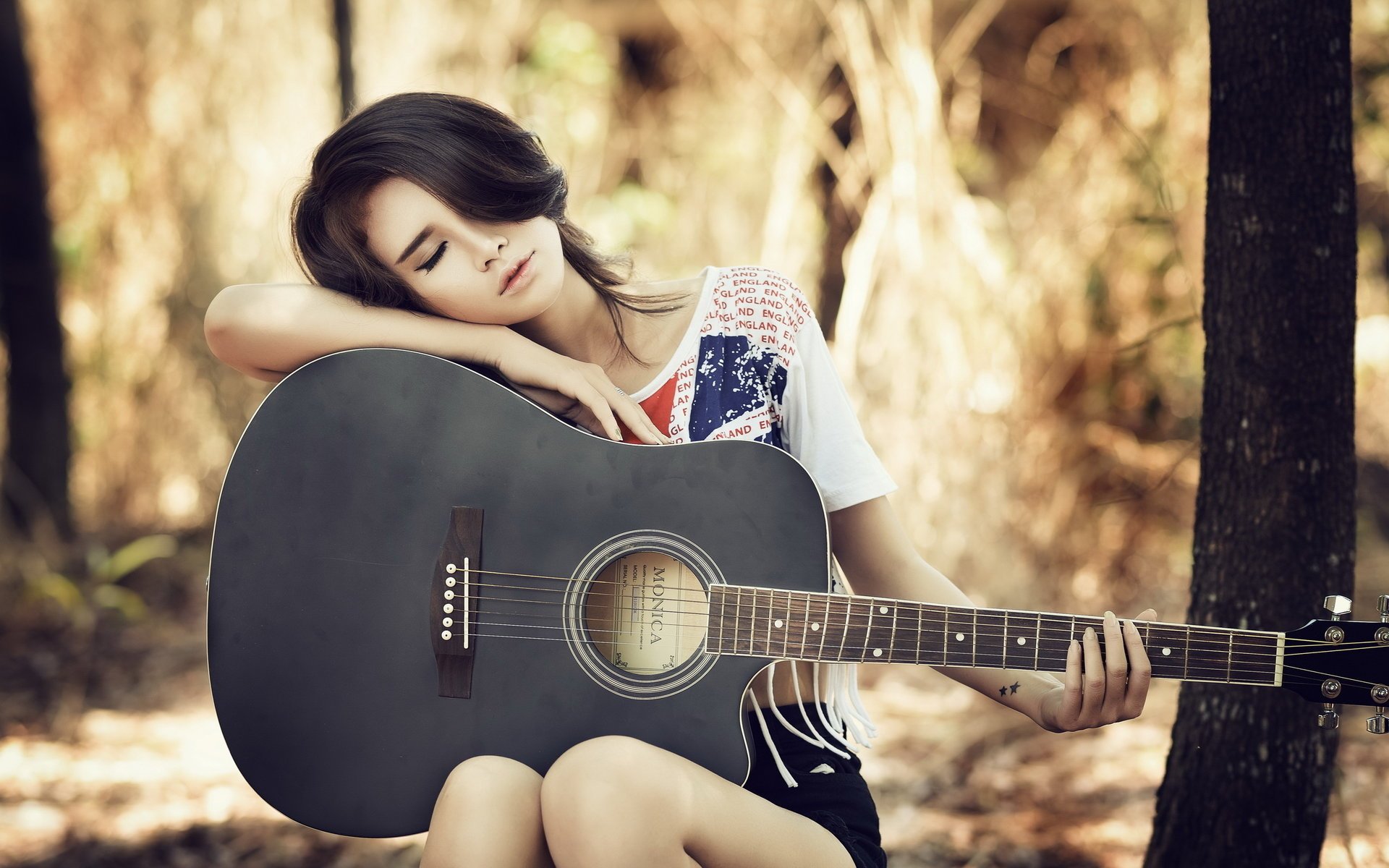 Азиатка обнимающая гитару в лесу