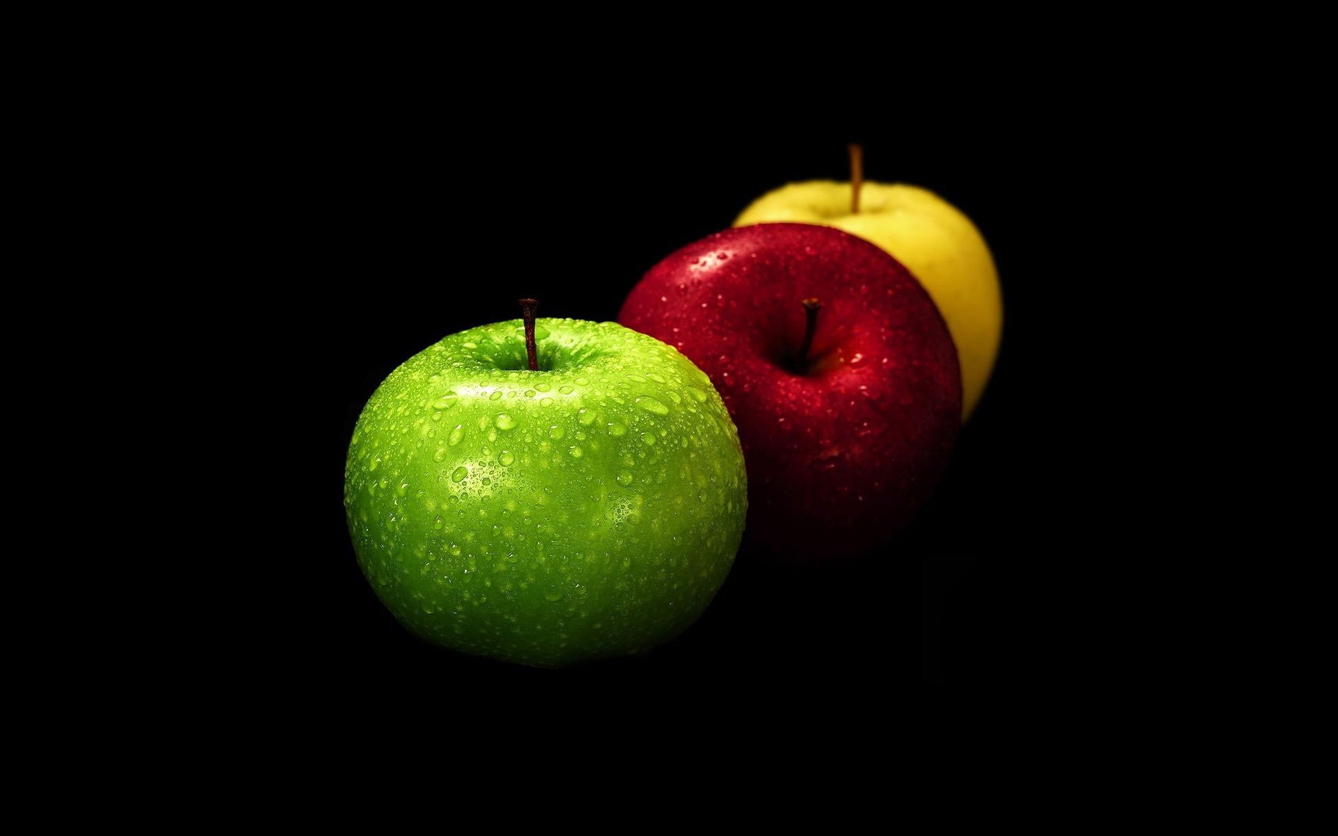 Натюрморт три разноцветных яблока на черном фоне