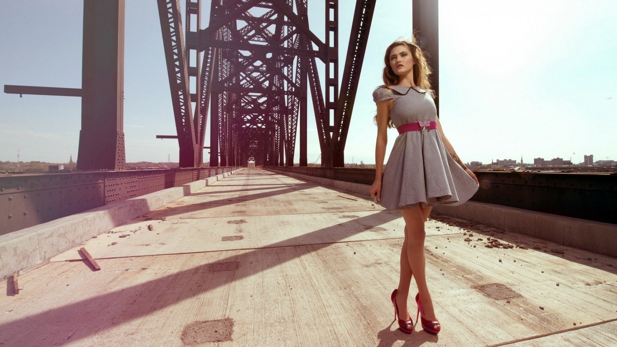 Стройная девушка в платье позирует на мосту