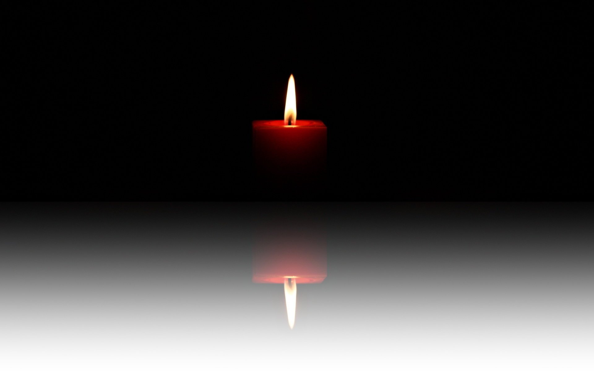 Отражение горящей свечи на белом фоне