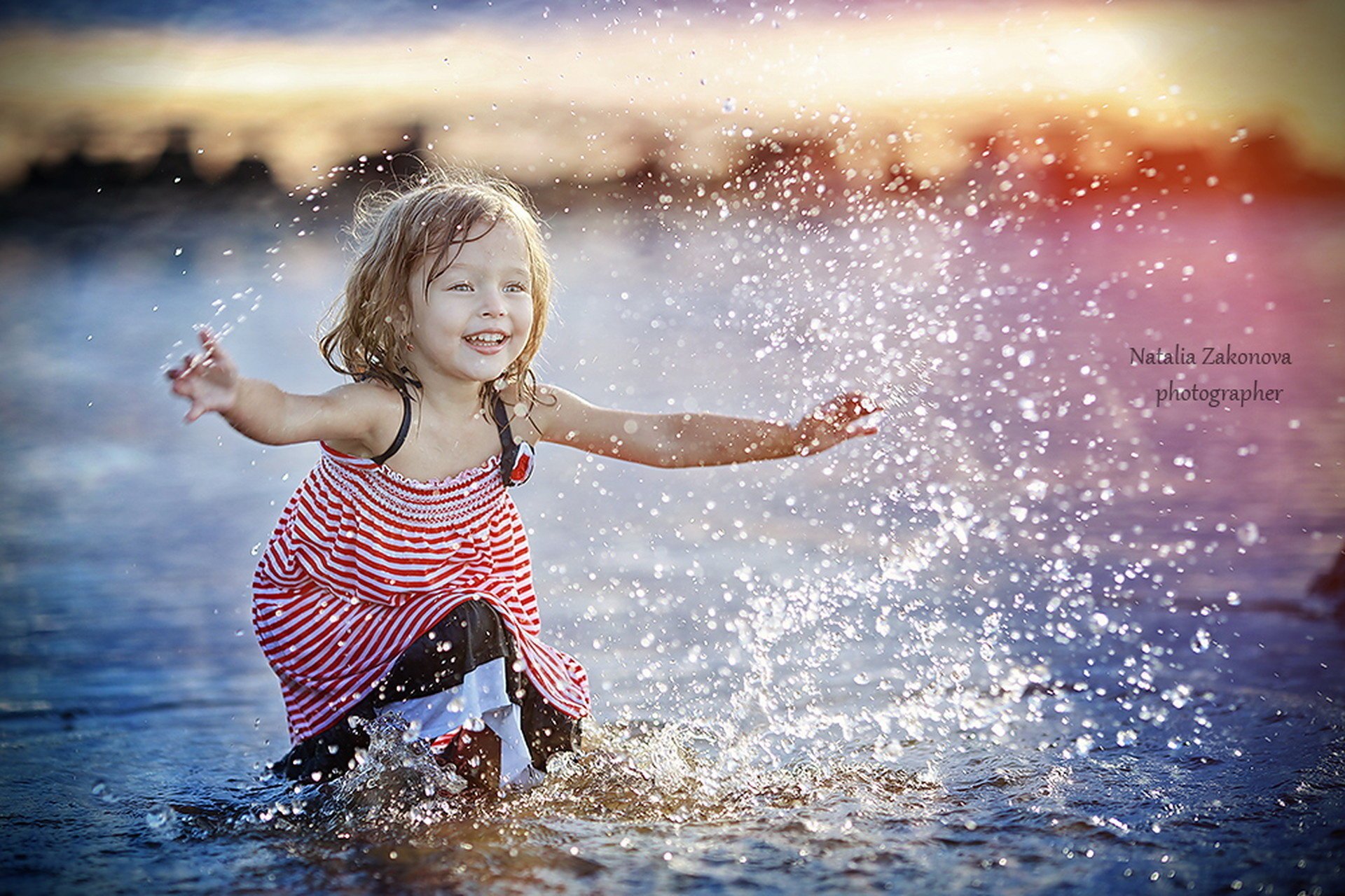Маленькая девочка играет в воде. Закат на берегу