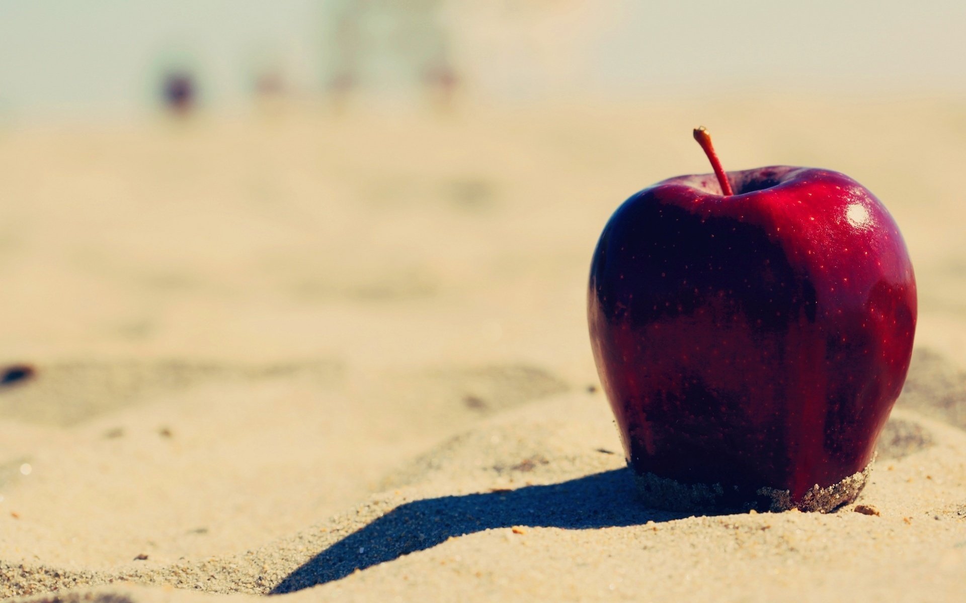 Красное яблоко на песочном пляже