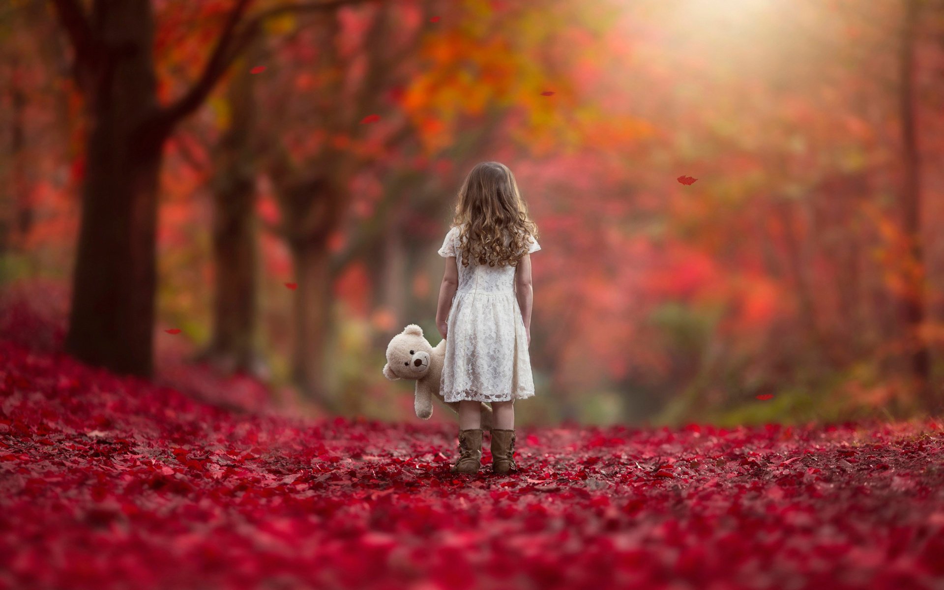 Девочка с плюшевым мишкой на фоне осеннего пейзажа